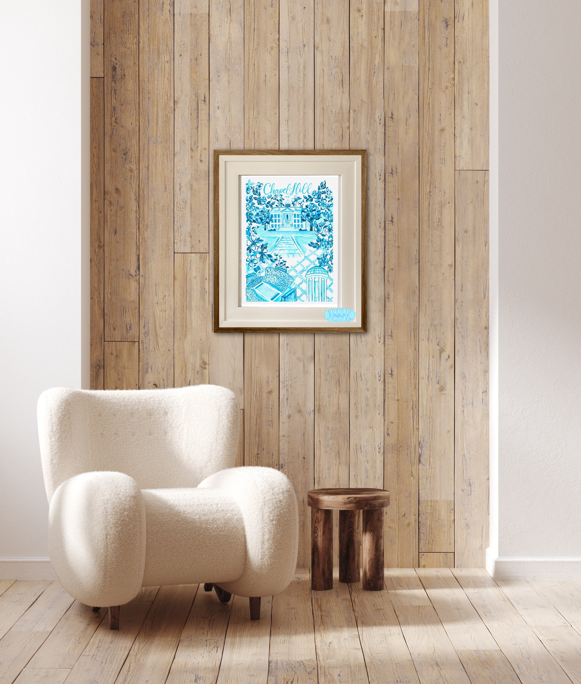 This bright blue toile art print is filled with floral details unique to chapel hill north carolina. The print is framed and rests on a wood paneled background.