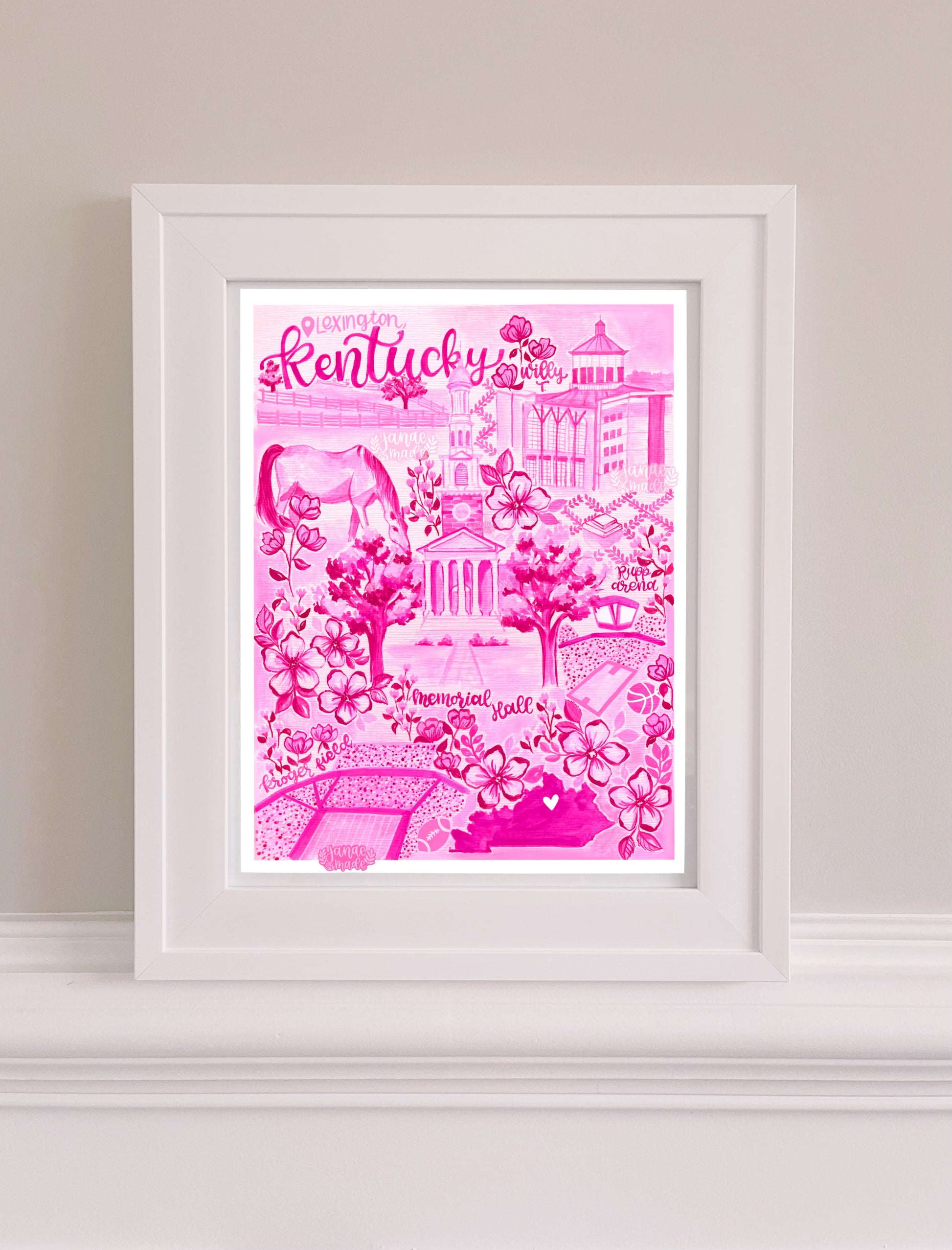 This a pink toile art print title with hot pink calligraphy hand lettering. This artwork features fun landmarks unique to Lexington, Kentucky! Art print is in a white frame.